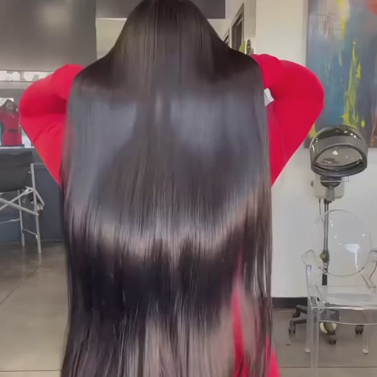 Woman with long black hair and a mannequin head with a wig on a gray background