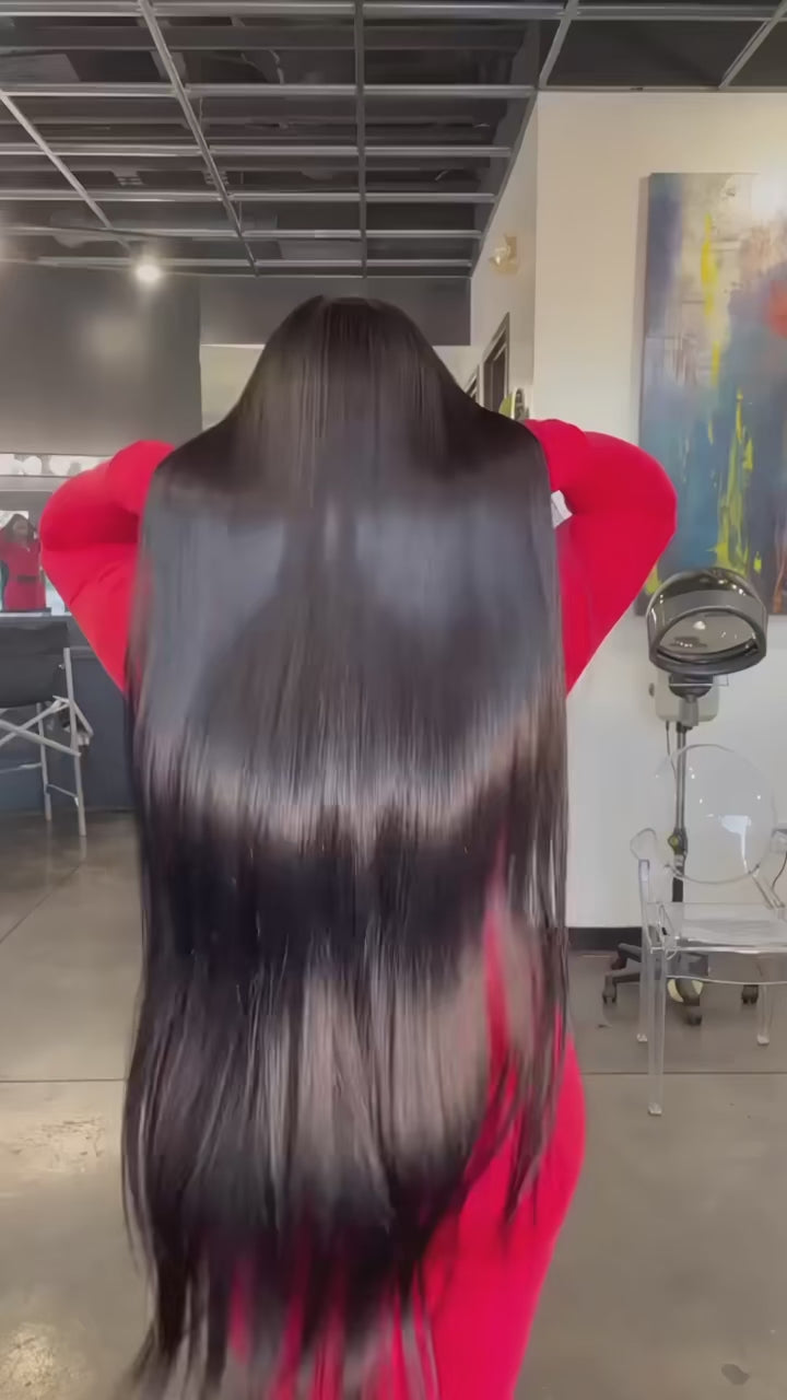 Woman with long black hair and a mannequin head with a wig on a gray background